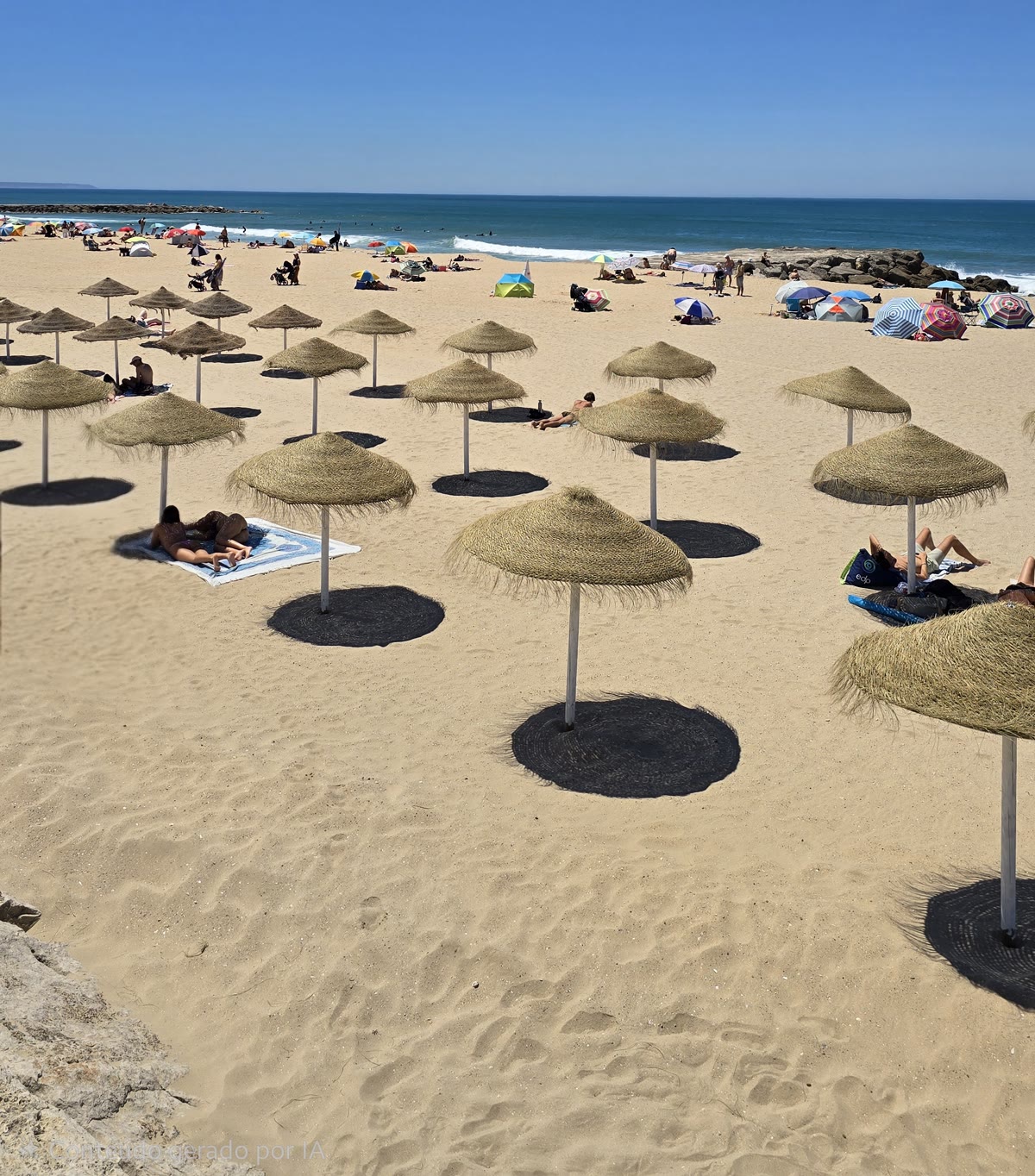 Praia de Santo António — areal com os chapéus de palha do Café do Mar, mar e céu de verão